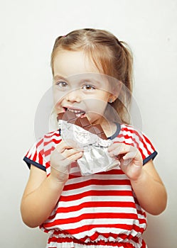 Lady of young age eating chocolate wrapped in tinfoil