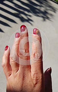 Ladybug on fingers with red nails, red atmosphere.