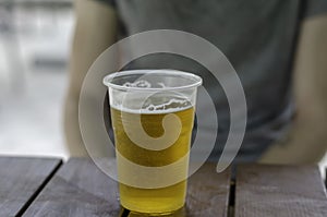 Lager beer in a disposable plastic glass on wooden table