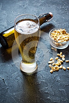 Lager beer glass and Peanuts on stone table