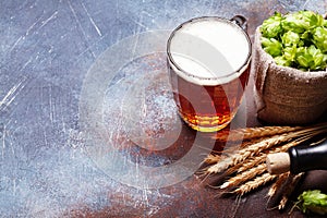 Lager beer mug, hops and wheat on old stone table