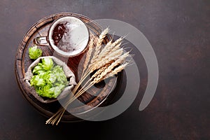 Lager beer mug, hops and wheat on old wooden barrel