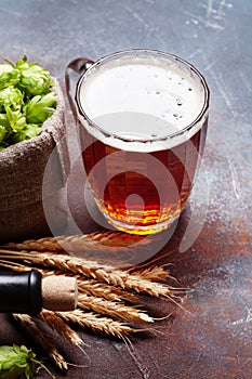 Lager beer mug, hops and wheat on stone table