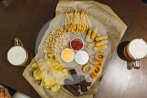 Lager beer and snacks on wooden table. Nuts, chips, peanut, toast, crackers. Appetizer fast food. Craft beer. Beerboard