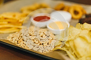 Lager beer and snacks on wooden table. Nuts, chips, peanut, toast, crackers. Appetizer fast food. Craft beer. Beerboard