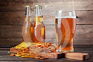 Lager beer and snacks on wooden table. Nuts, chips, pretzel