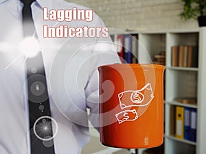 Lagging Indicators phrase. Man with a cup of coffee in the background