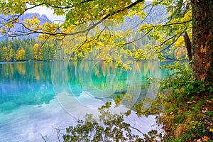 Laghi di Fusine inferior lake, Tarvisio, Italy. Autumn landscape with water, forest and Mangart mountain, nature travel background