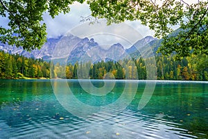 Laghi di Fusine inferior lake, Tarvisio, Italy. Autumn landscape with water, forest and Mangart mountain, nature travel background