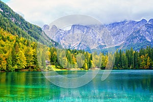 Laghi di Fusine inferior lake, Tarvisio, Italy. Autumn landscape with water, forest and Mangart mountain, nature travel background