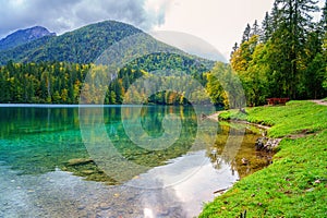 Laghi di Fusine inferior lake, Tarvisio, Italy. Autumn landscape with water, forest and Mangart mountain, nature travel background