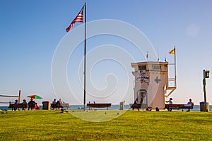 Laguna Beach, California - October 9, 2018: Lifeguard tower and flagpole with American Flag with grassy foreground at Laguna beach