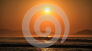 Surfer surfing at sunrise on the beautiful coast of the Chacahua National Park, Oaxaca, Mexico