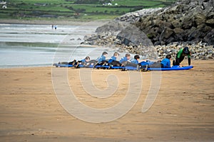 Lahinch / Ireland 08/06/2020: Couch teaches a group young boys surfing on a beach, kids dressed in wet suits