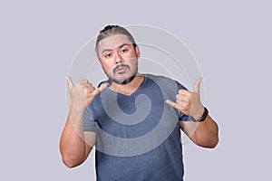 A laidback dude in a gray shirt makes a double shake sign. Telling someone to take it easy and chill photo