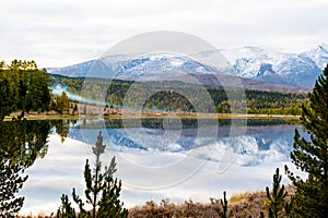 Lake, Altai, Siberia, cloudy autumn day. Taiga, beautiful sky, haze, snow-capped mountains