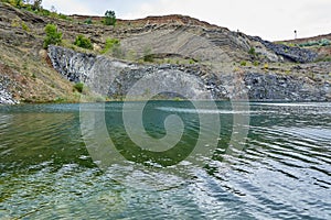 Lake in an ancient quarry with various types of rocks