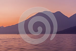 Lake Atitlan and volcanoes and boat in the morning