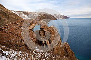 Lake Baikal on a cloudy December day. A mountain landscape, a hole in a rock or a window of desires near Aya Bay