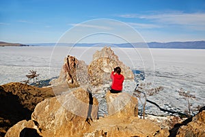 Lake Baikal during the melting of the ice. A female traveler takes photos of Cape Burkhan
