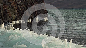 Lake Baikal water wave make frozen ice splash on rock cliff and floe crack on shore. Broken block