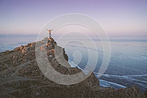 Lake Baikal at winter. Man standing on a edge of cliff and looking at frozen Baikal lake.