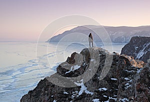 Lake Baikal at winter. Woman standing on a top of mountain and staring at frozen Baikal lake