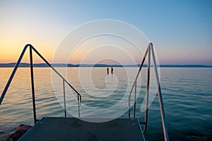 Lake Balaton at sunset with bathers and a stairs to the water photo