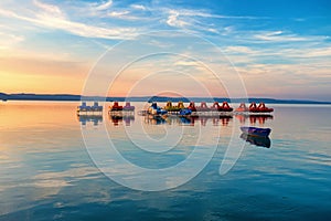 Lake Balaton at sunset with pedalos, kayaks and a boat in the foreground