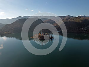 Lake Bled island with sun rays in the snowless winter aerial