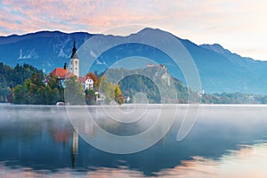 Lake Bled in the morning. Church on island, castle and mountains in background