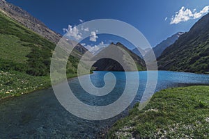 Lake with blue clear clear water in mountains in summer. Koksai Ainakol Lake in Tien Shan Mountains in Asia in