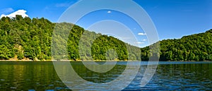 Lake Bystrzyckie located in a mountain valley, green forest on the slopes of the mountains, the view from the lake shore.