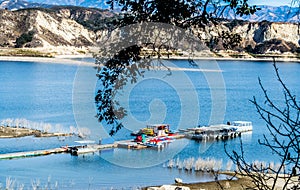 Long wooden pier and boats at California`s Lake Cachuma with San Rafael Mountains