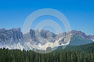 Lake Carezza an alpine lake surrounded with tall pine forest in the Dolomites with Rosengarten mountain range view background in