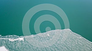 The lake is covered with green ice. The lake freezes. A top view shot with a drone.