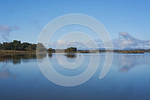 Lake dam landscape with reflection of Gardunha mountains and trees on a cloudy day in Santa Agueda Marateca Dam in Portugal photo