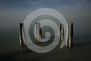 Lake dock wooden poles after the morning fog