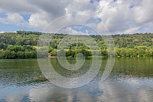 Lake Echternach with its calm water, hills with abundant leafy trees in the misty background