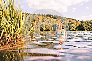 Lake in Finland. Happy smiling woman swimming in water summer. Finnish nature at sunset. Pretty girl in swimsuit or bikini.