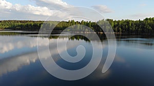 Lake, forest and yellow field in spring sunrise light 4k aerial top view. Fly above water of lake Dolgoe, Belarus.