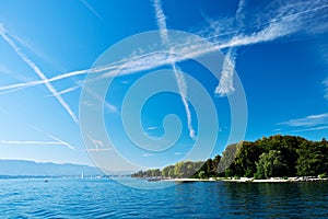 Lake Geneva with many aeroplane jet trails in the sky