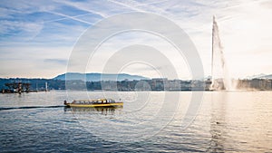 Lake Geneva panorama with the famous Jet d'Eau or water jet and small yellow shuttle boat Geneva Switzerland