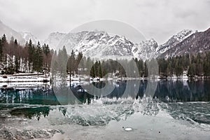 Lake with green forest and snowy mountains in the background and skyfall effect. Italian lake during winter with photo