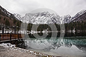 Lake with green forest and snowy mountains in the background and skyfall effect. Italian lake during winter with photo