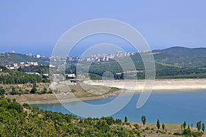 lake with hills near the town on a summer day