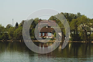 Lake house. house on the shore in the village. landscape with reflection on the water