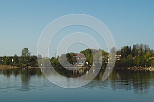 Lake house. house on the shore in the village. landscape with reflection on the water