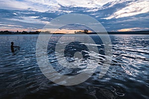 Lake Itza during sunset with silhouette of a person swimming, Flores, Peten, Guatemala