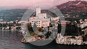 Lake Lago Garda - view of Malcesine village. Old castle on rock Italy. Aerial video sunset